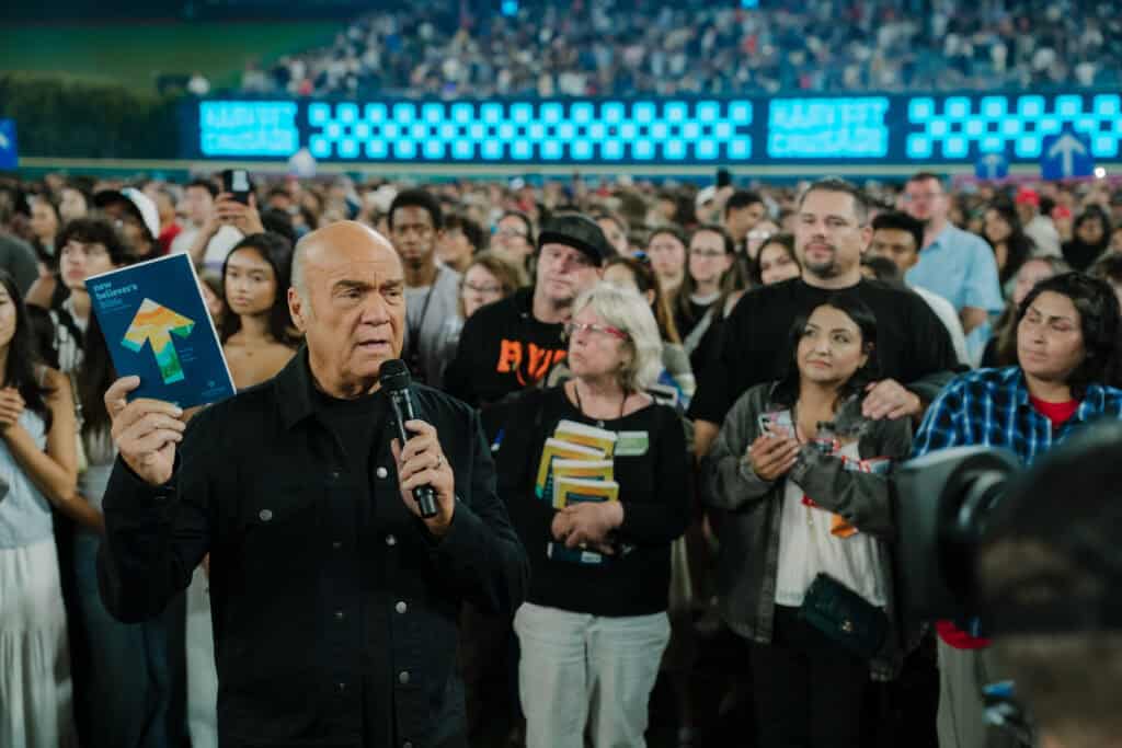 Greg Laurie holds up bible at 2025 harvest crusade with crowd