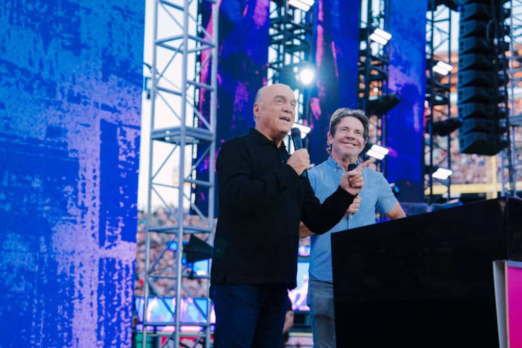 Dennis Quaid and Greg Laurie speaking together on stage at the 2024 Harvest Crusade